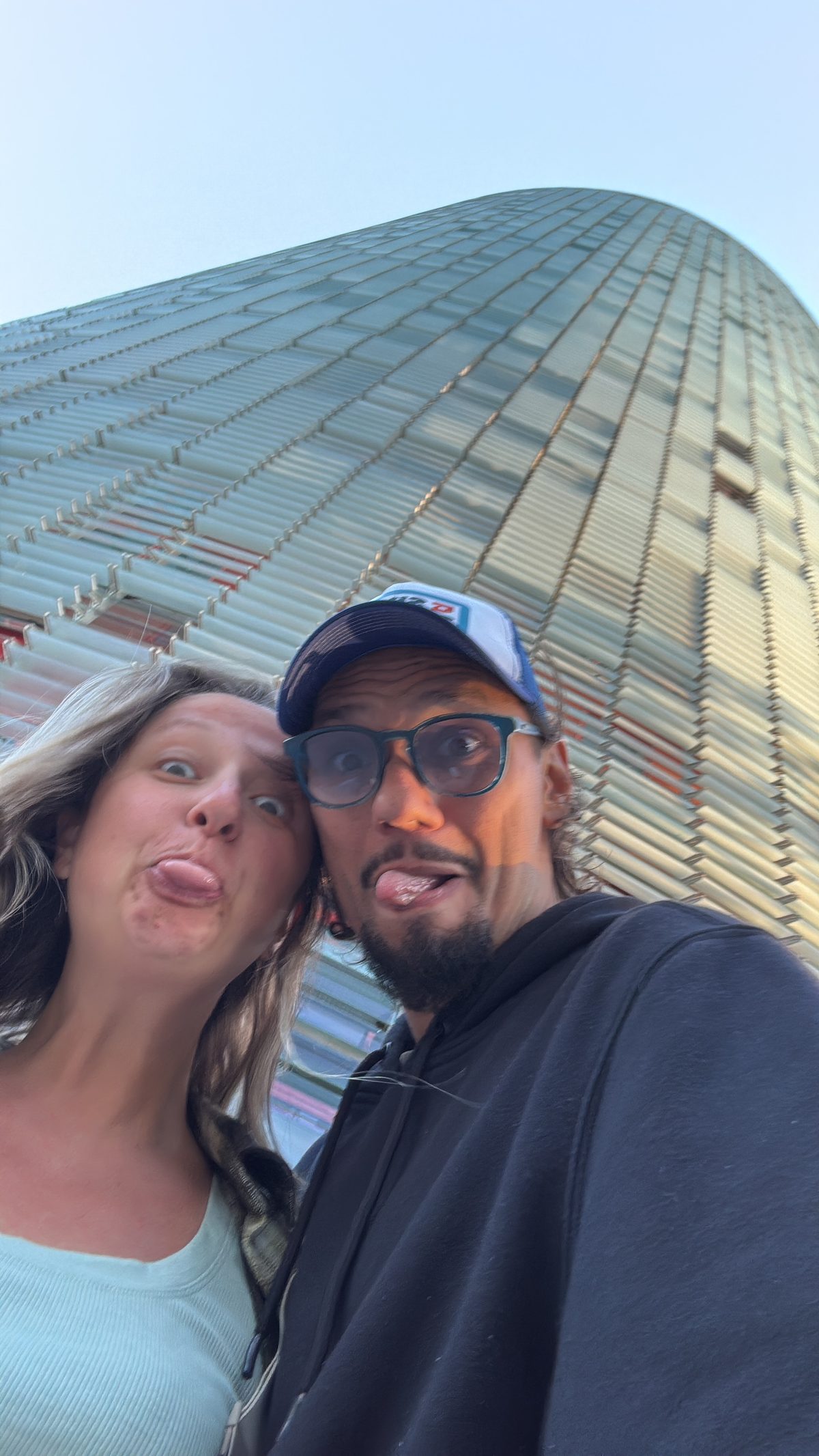 Vini and Adri pulling faces under the Torre Glòries in Barcelona.